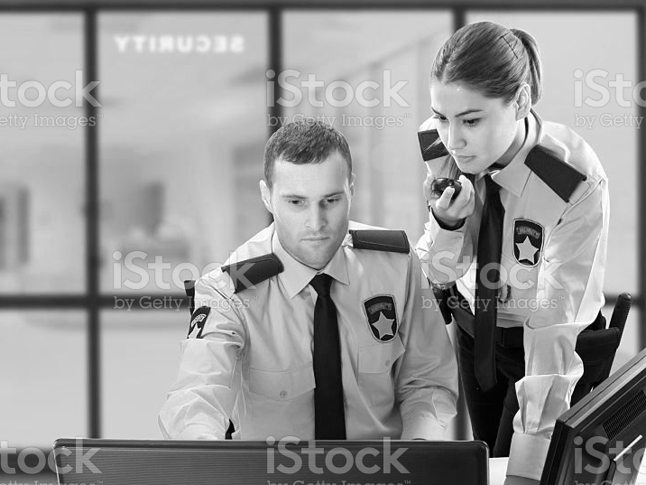 Zwei Sicherheitsmitarbeiter arbeiten sitzend an einem Bildschirm